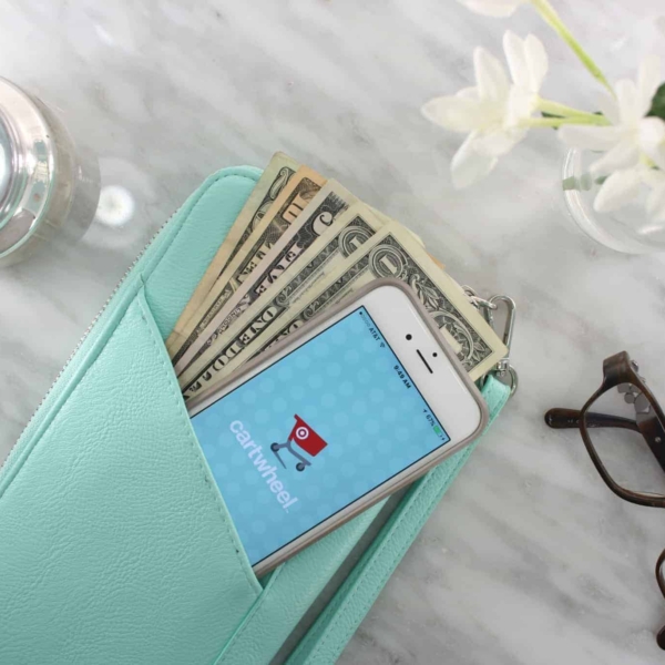 a wallet with money and a phone on a table next to glasses and some flowers