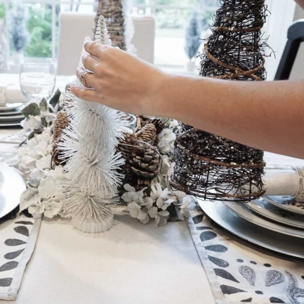 Decorating the dining room table centerpiece with a variety of tree decor.