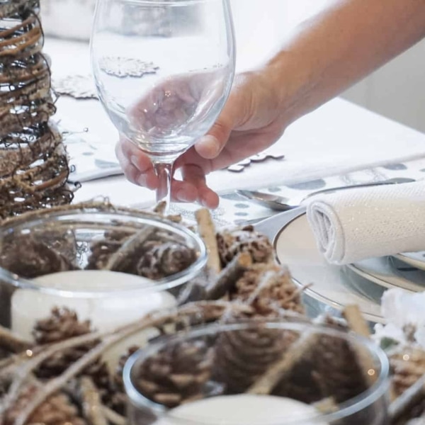 Placing a wine glass with a Christmas place setting in the dining room.