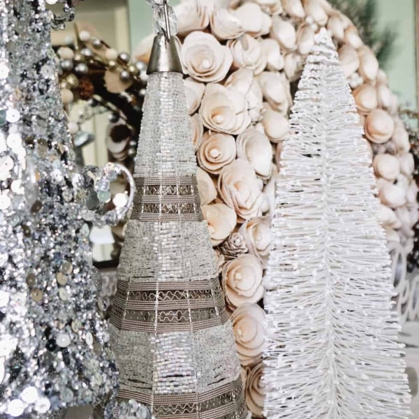 A dining room buffet decorated with white and sparkly tree decor with a wood flower wreath in the background.