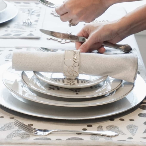 Placing silverware for a Christmas dining room place setting.