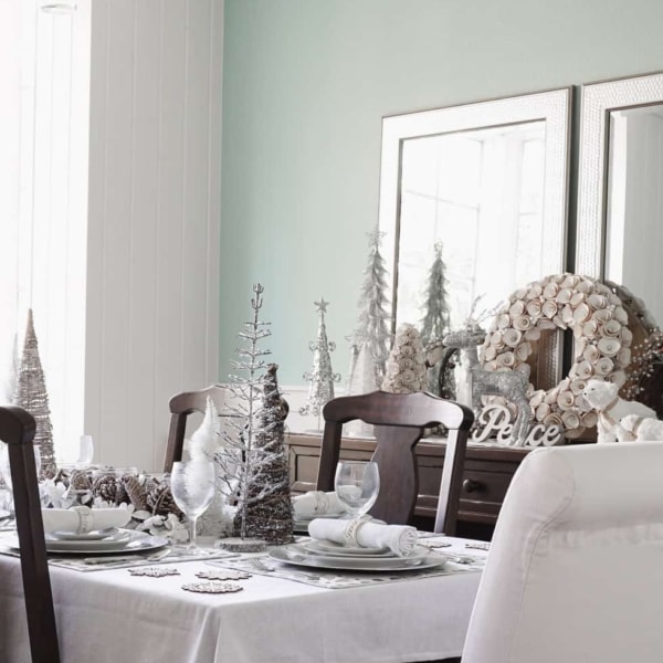 An entire dining room decorated for Christmas with woody, muted, and frosted decor pieces. The buffet is decorated with decorative trees of all sizes, textures, and materials, wreaths, and woodlands creatures including small polar bears.