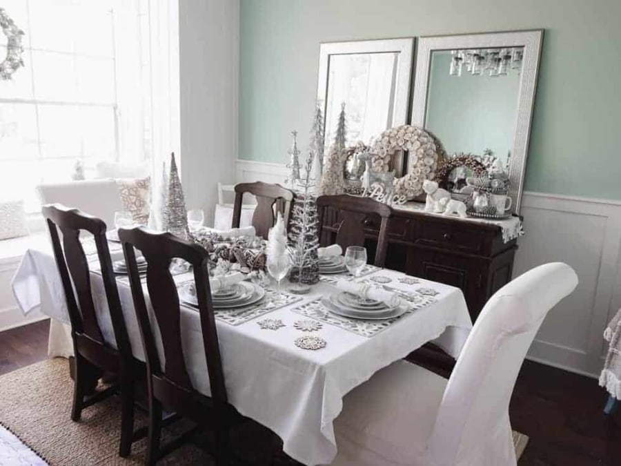 Beautiful Christmas dining room decor ideas including place settings, table centerpiece, wreaths, decorative Christmas trees, and Christmas animals. 