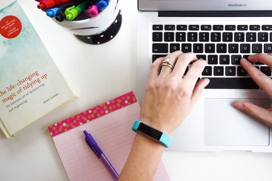 typing on a computer next to a book titled the life-changing magic of tidying up