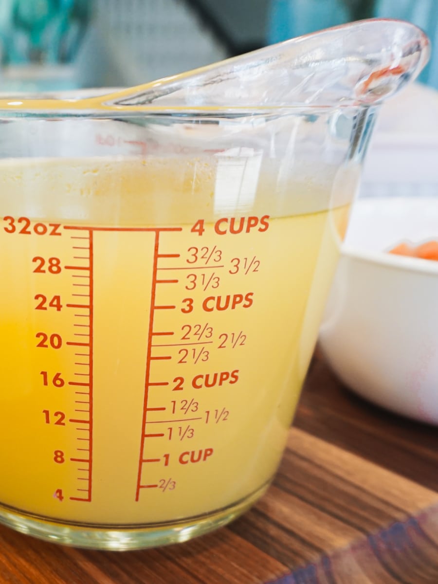 Four cups of unsalted chicken stock in a measuring cup.