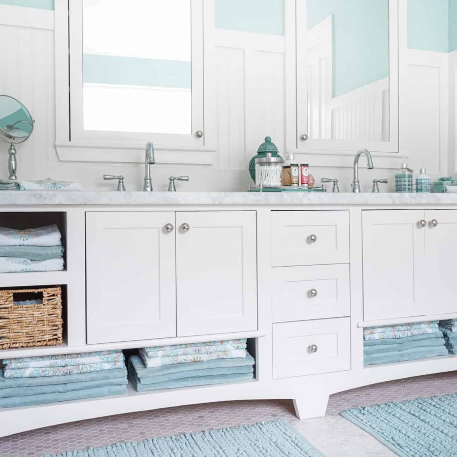 a spotless bathroom with clean towels, mats, and sinks