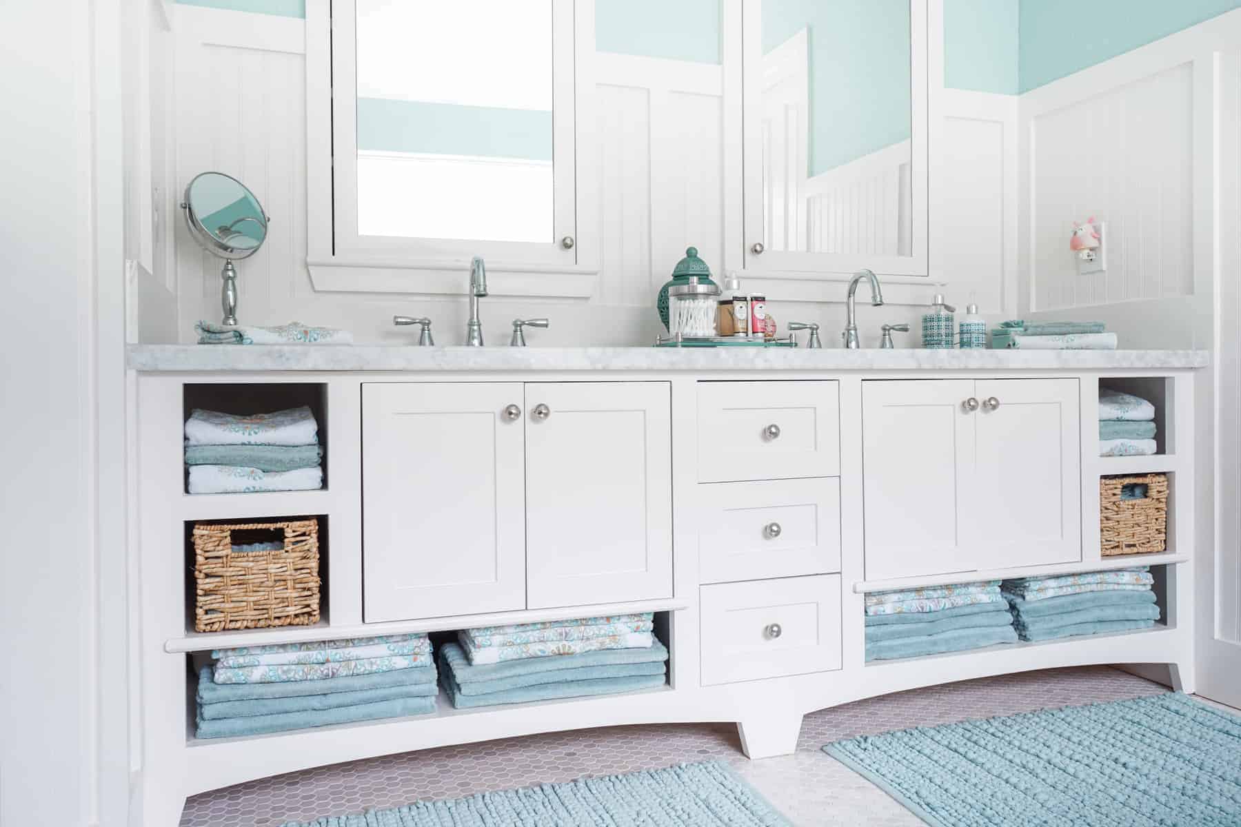 a spotless bathroom with clean towels, mats, and sinks