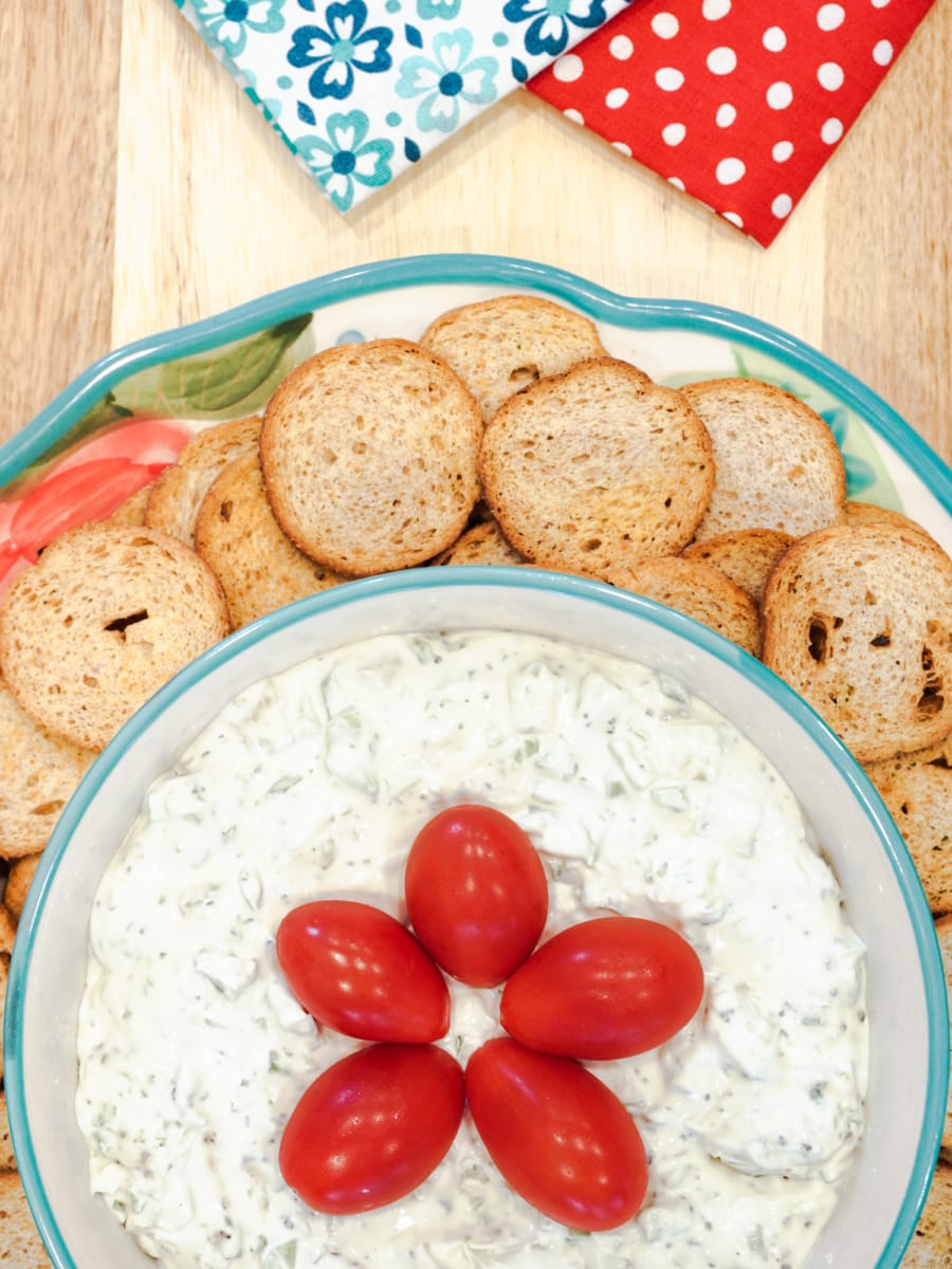 a bowl of cream cheese dip on a plate with bread crackers