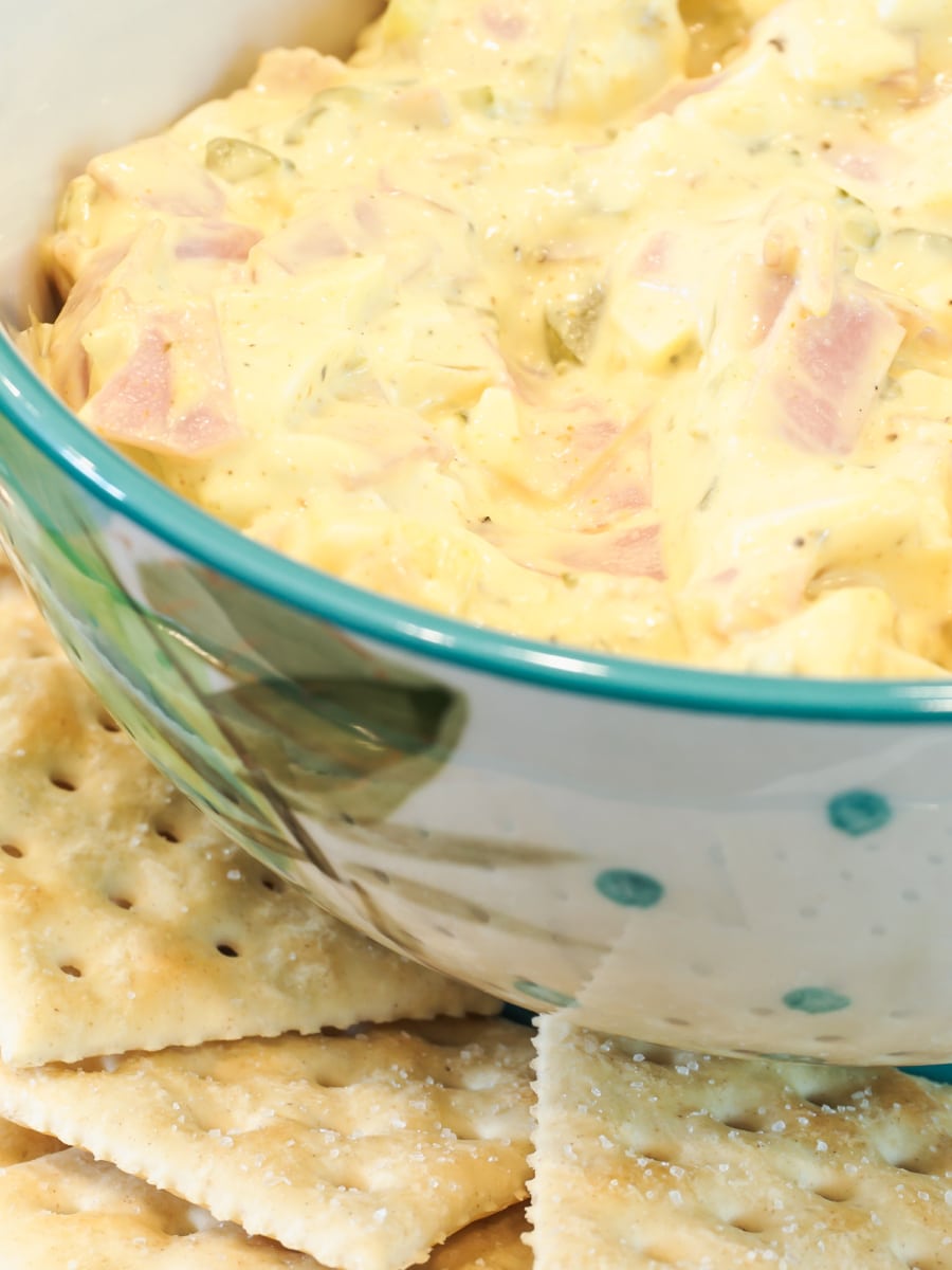 ham and egg dip in a bowl served on a plate with crackers