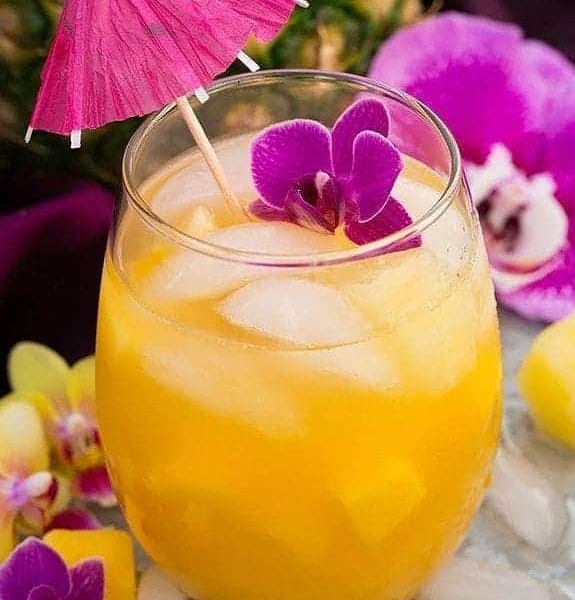 pineapple mango lemonade topped with a mini umbrella a flower pedals