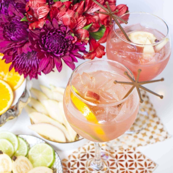 a sangria mocktail next top some flowers and different limes and lemons