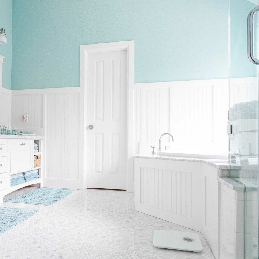 White tile and cabinets allow you to decorate your bathroom in any color scheme by swapping out bath mats and towels.