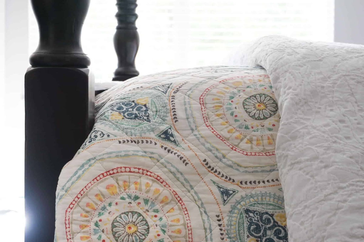 Decorate with color by using a colorful quilt layered on white bedding.