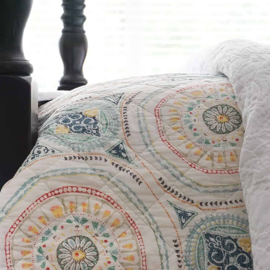 Decorate with color by using a colorful quilt layered on white bedding.