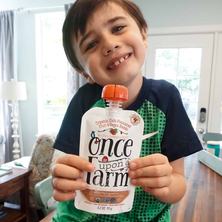 a boy holding a drinkable pouch with a healthy fruit blend