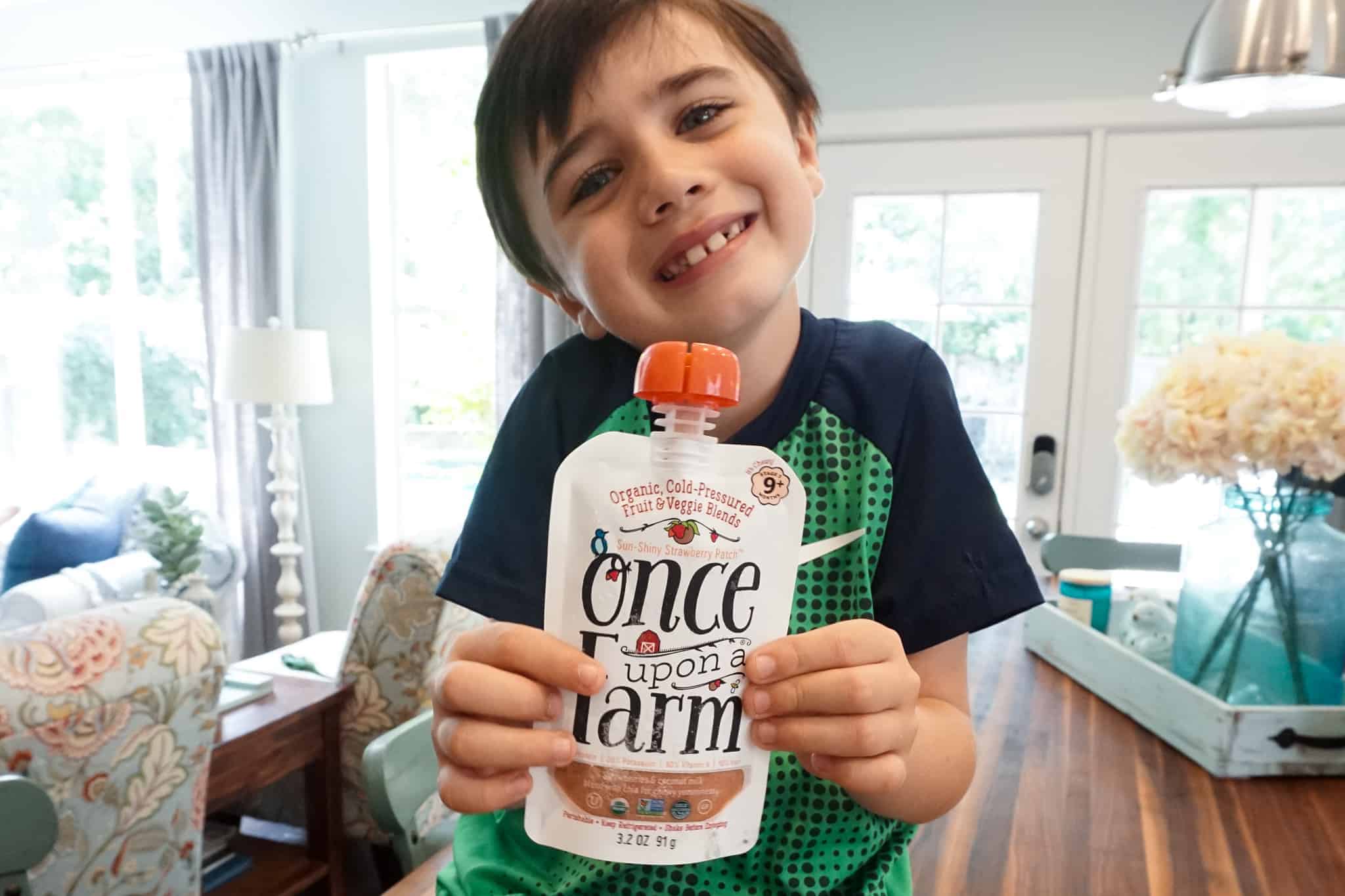 a boy holding a drinkable pouch with a healthy fruit blend