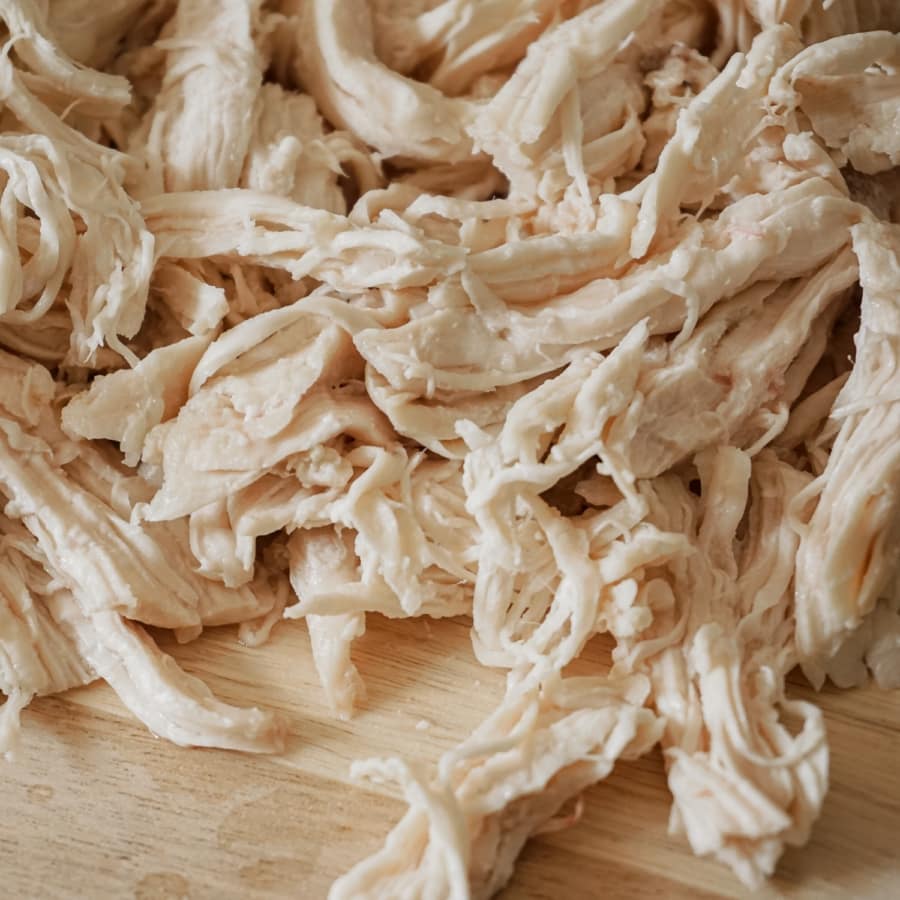 freshly made shredded chicken on a wooden board