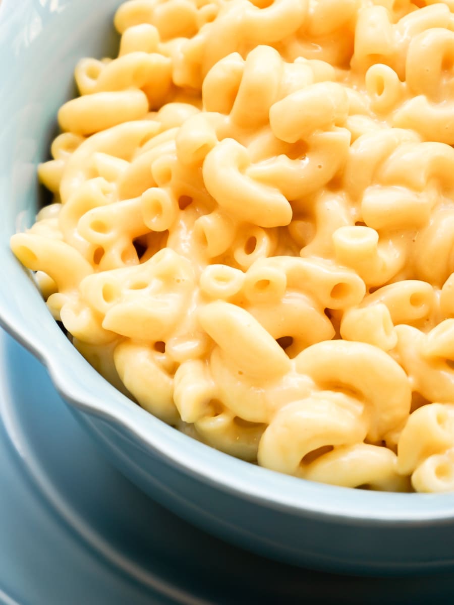 a warm and creamy bowl of mac and cheese sitting next to a spoon