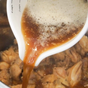 Pouring a sweet Hawaiian Chicken sauce over chicken thighs in the Instant Pot.