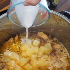 Adding a thickening agent to the Hawaiian chicken thighs in the Instant Pot.