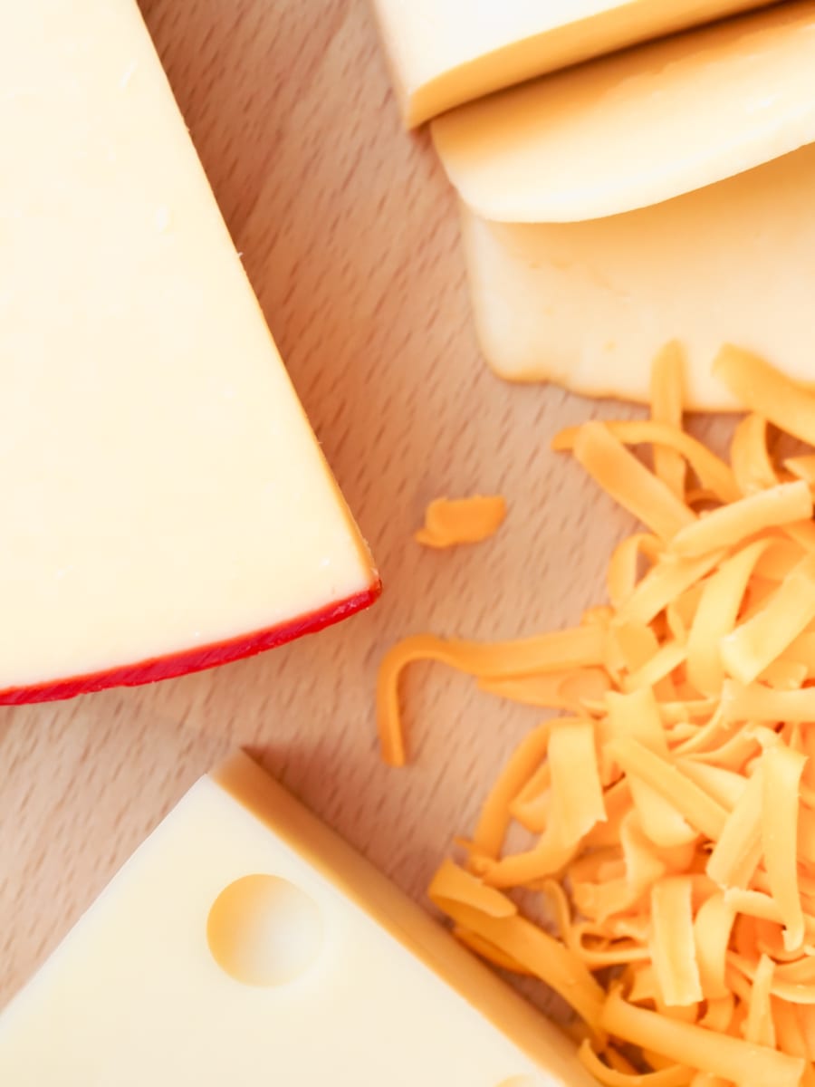 overhead shot of four different cheeses on a wooden board