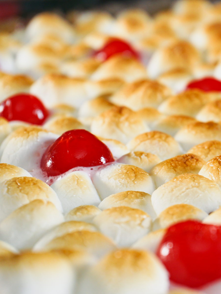 close up of a sweet potato casserole topped with marshmallows and cherries