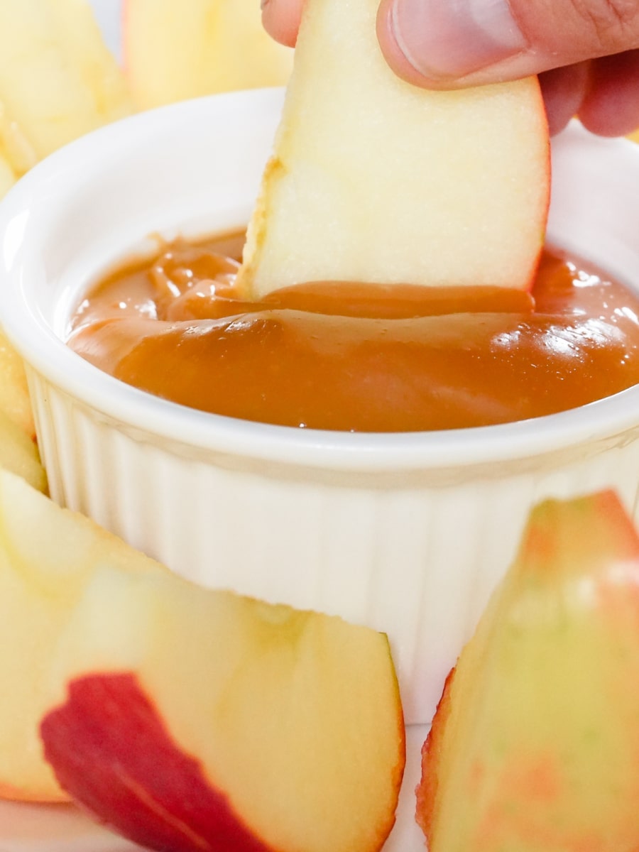 dipping a apple slice in a small bowl of dulce de leche