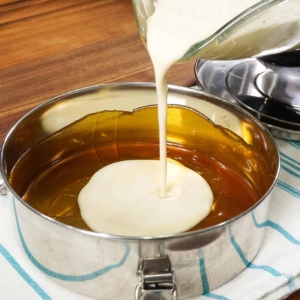 adding condensed milk to flan pan