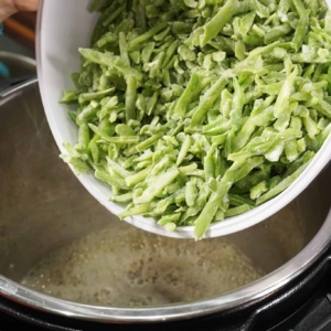 Adding a bowl of frozen green beans to the Instant Pot