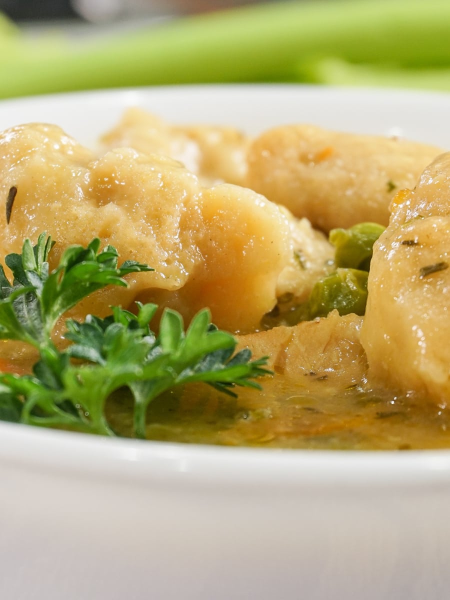 a bowl filled with chicken and biscuits garnished with parsley