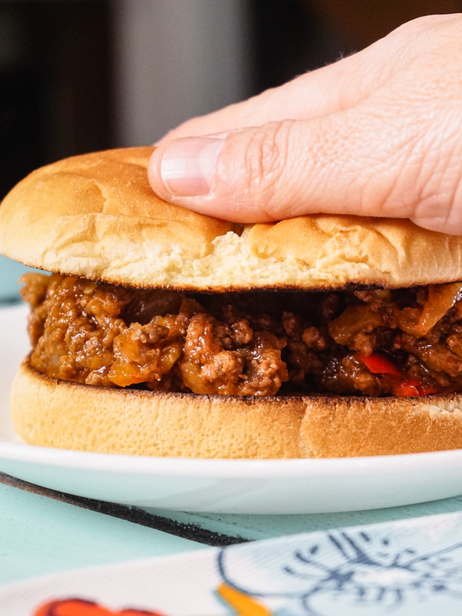 adding top bun to a sloppy joe sandwich