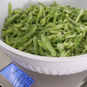 A bowl of french cut green beans being weighed on a scale before being put into the Instant Pot