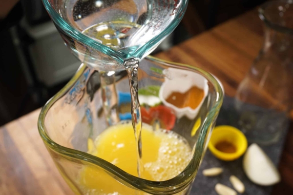 adding orange juice to the blender to make the sauce for this authentic mexican pork recipe