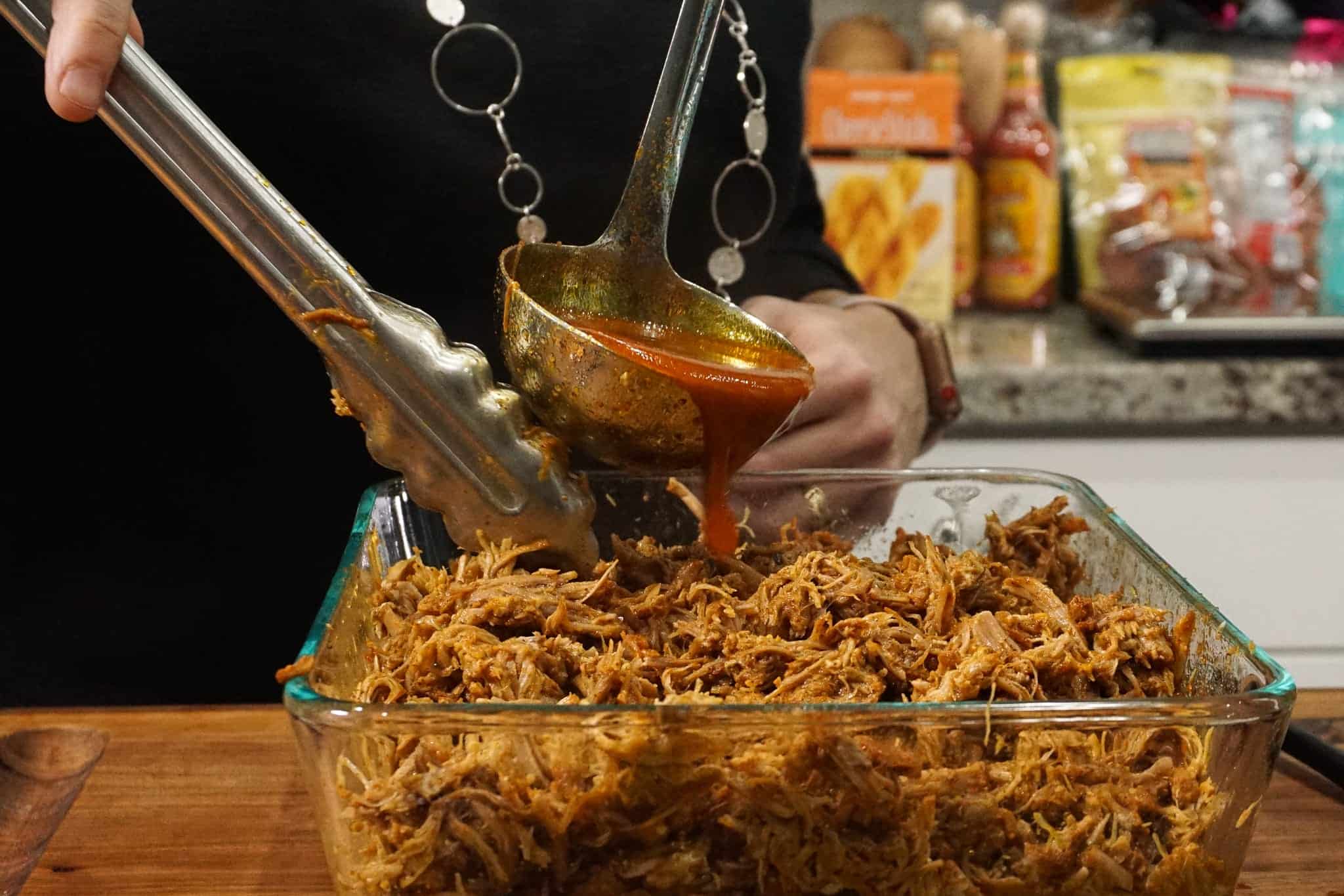 adding and mixing in more sauce to pulled pork