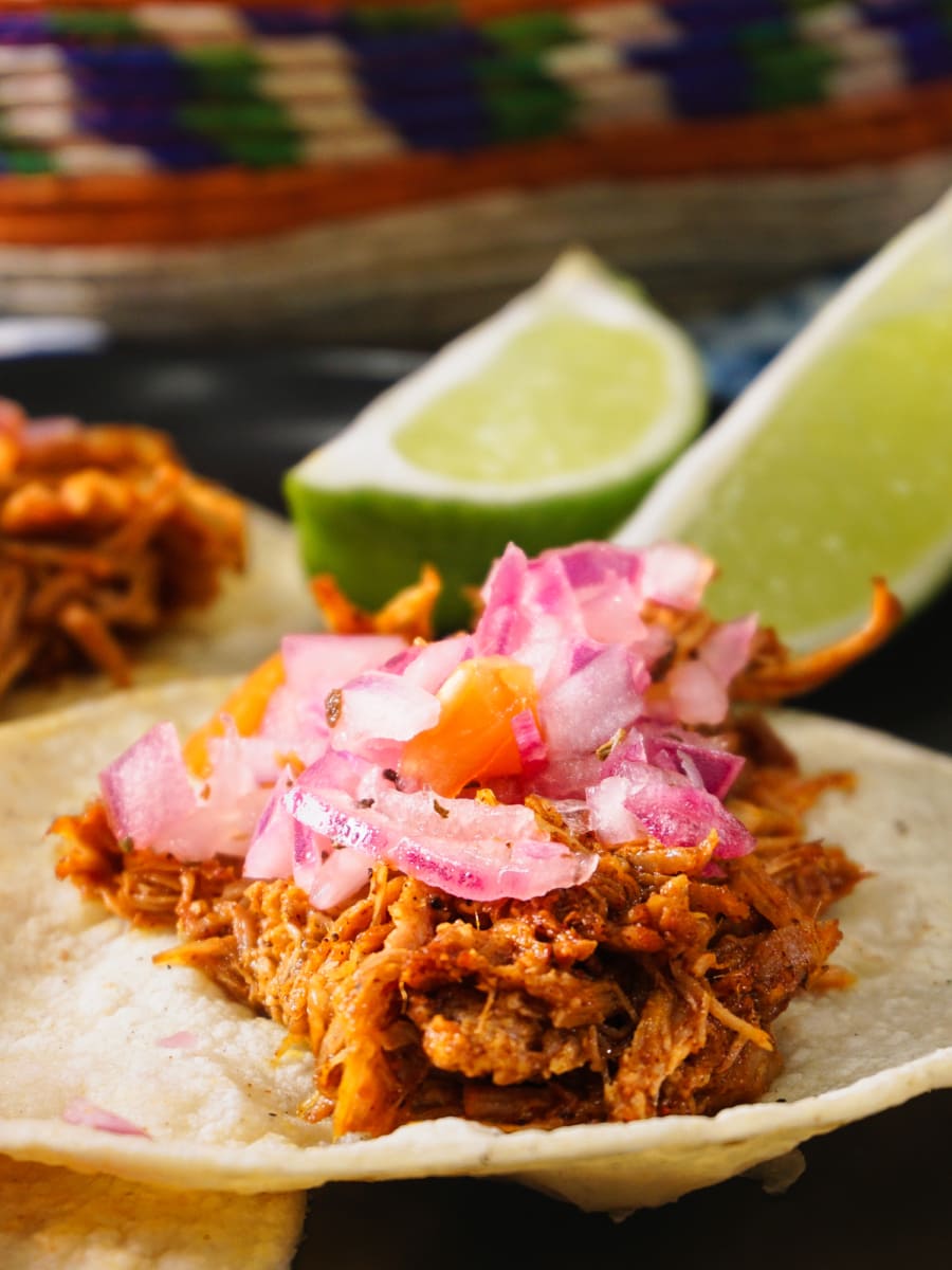 a plate of mexican shredded pork tacos served with a wedge of lime