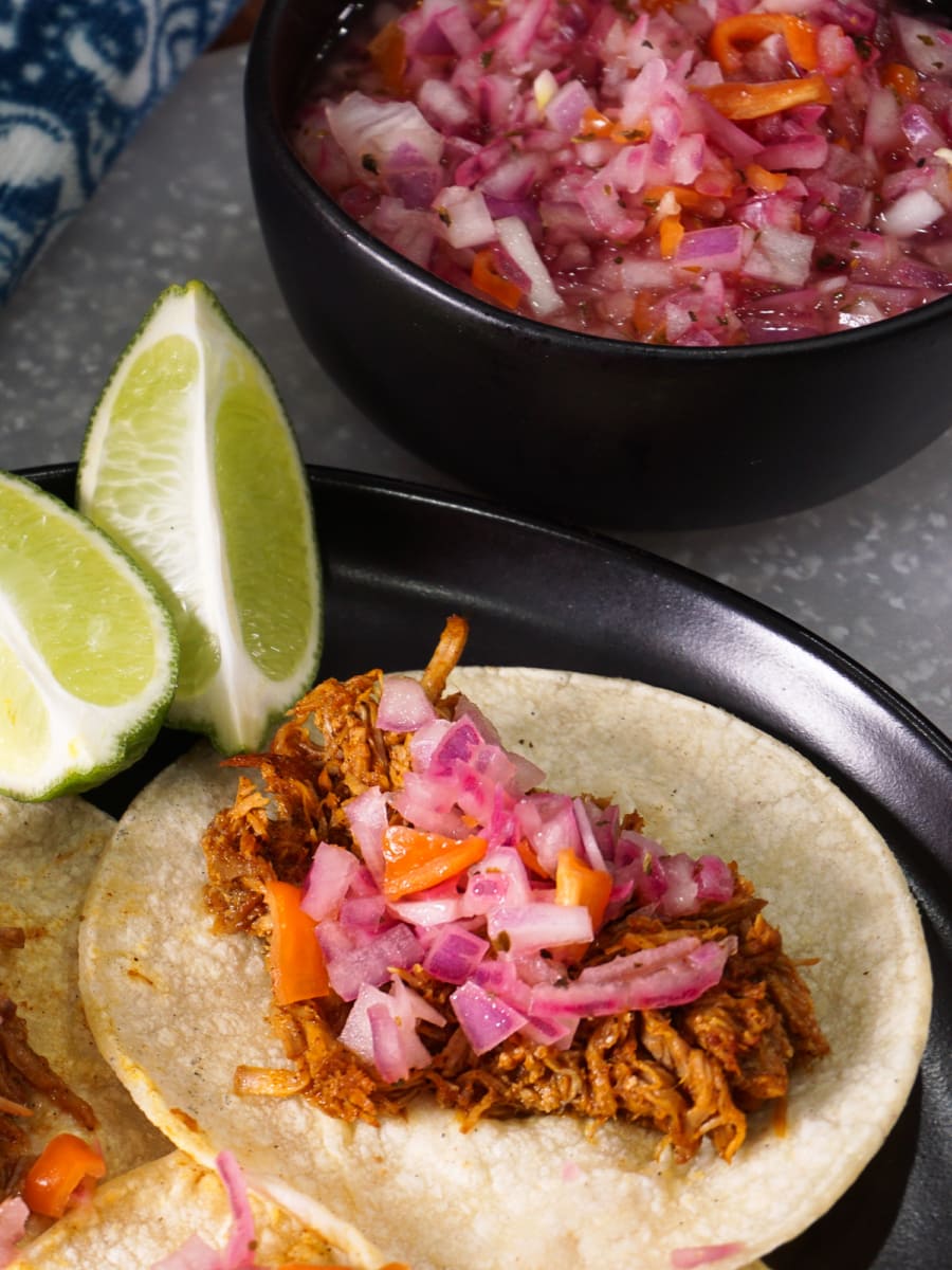 a plate of pork tacos topped with habanero salsa