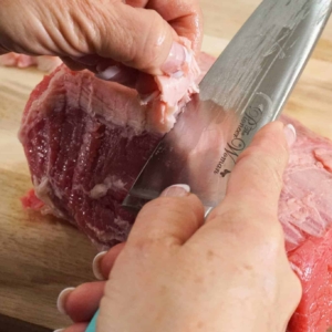 using a knife to cut the fat from beef round roast to prep for this instant pot salpicon recipe