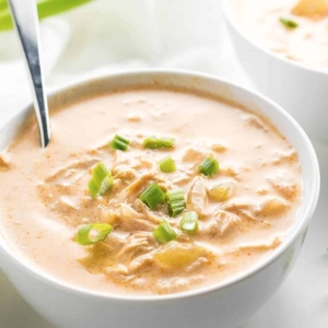 a bowl filled with buffalo chicken soup garnished with green onion