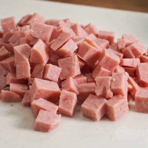 chopping cubes of spam for the best pasta salad recipe