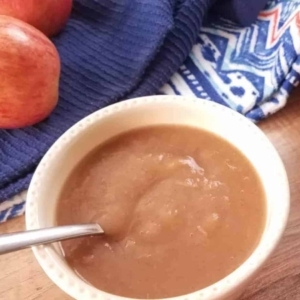 a bowl of  apple sauce next to some apples