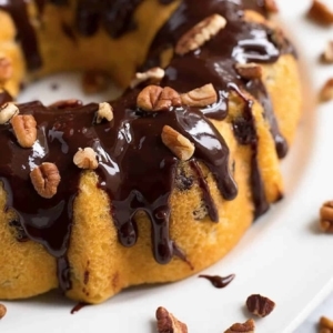 close up of a pecan chocolate chip cake drizzling with chocolate glaze