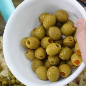 adding olives to the macaroni salad