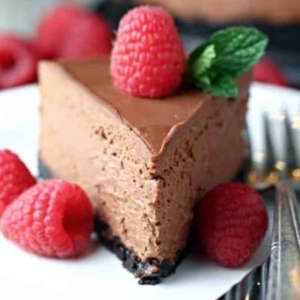 a slice of chocolate cheesecake on a plate topped with raspberries