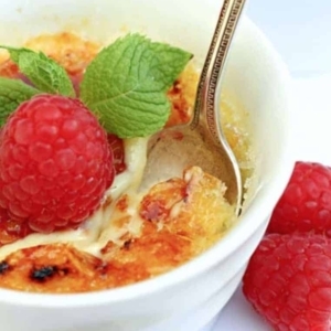 a creme brulee topped with a fresh raspberry