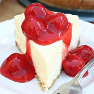 a creamy slice of a new work cheesecake topped with cherries