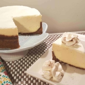 a partially cut into new york cheesecake on a cake stand