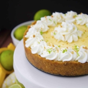 key lime pie on a cake stand with limes nearby