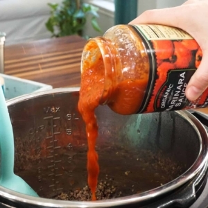 adding marinara sauce to lasagna meat sauce