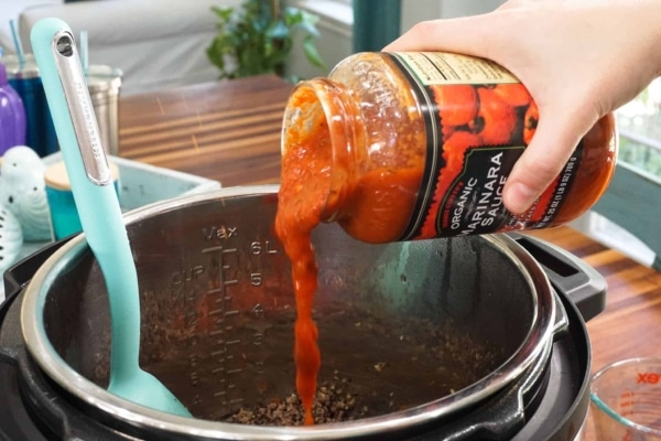 adding marinara sauce to lasagna meat sauce