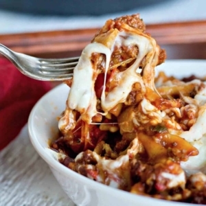 grabbing a large bite of meaty italian pasta from a bowl with a fork